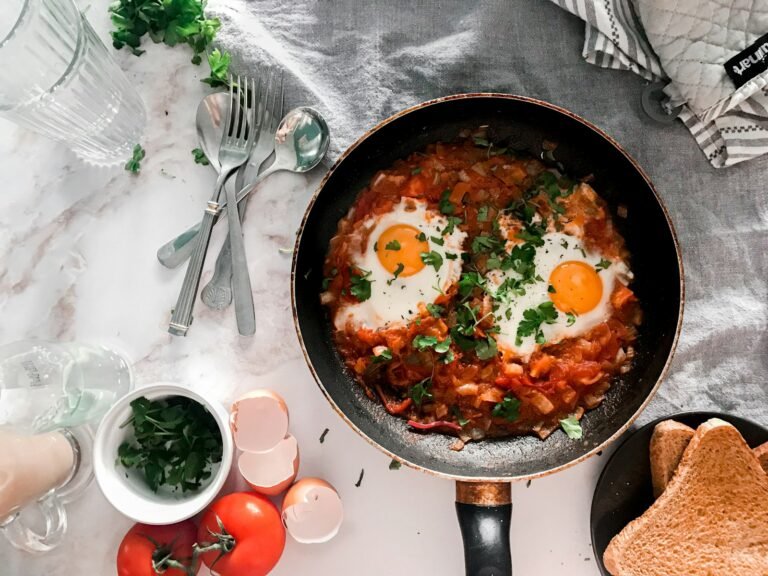 tomato soup on black cooking pan beside stainless steel fork and bread knife